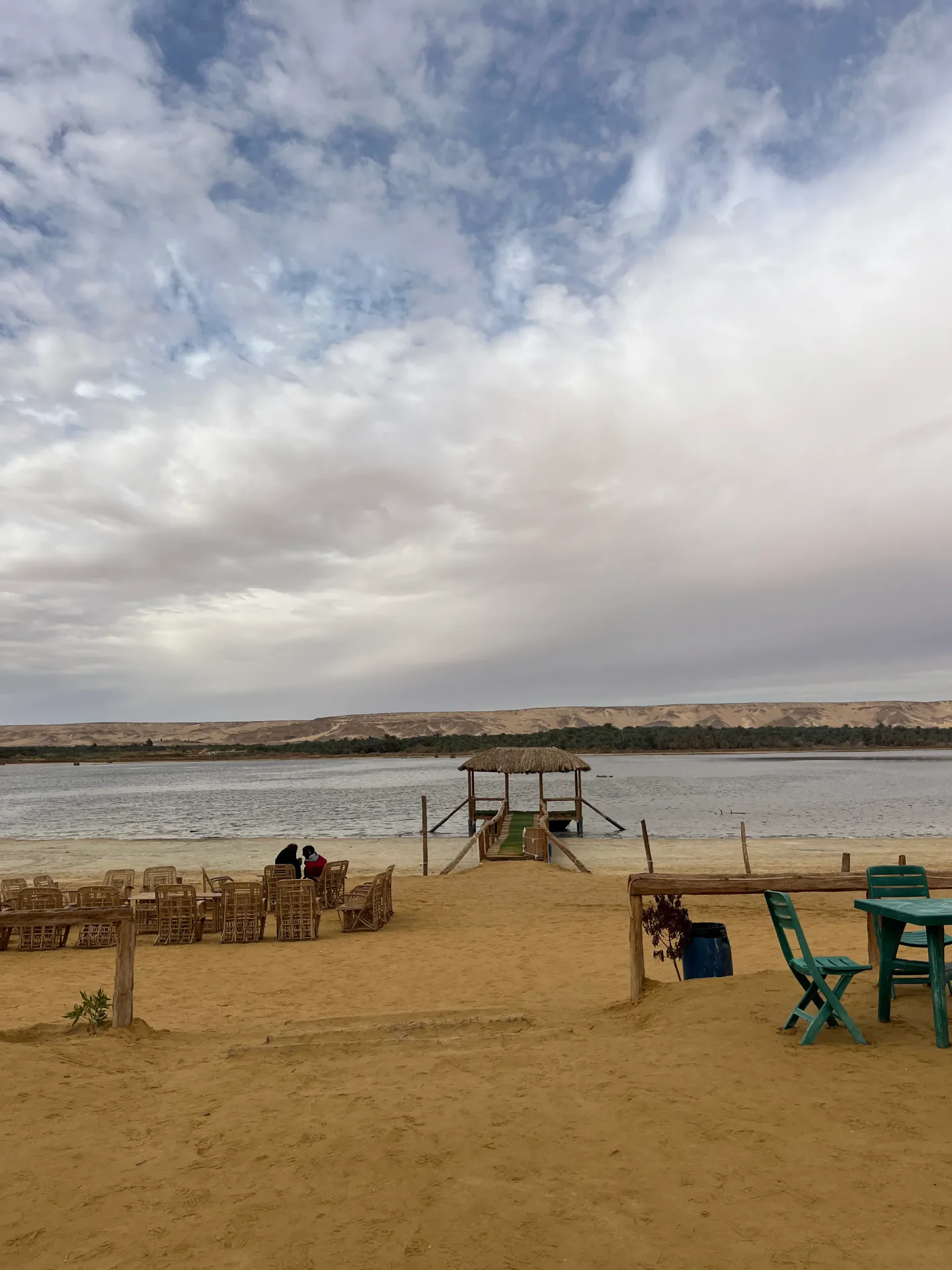 Travelers resting beside the salt lake and palm groves of Bahariya Oasis during the 2027 eclipse tour