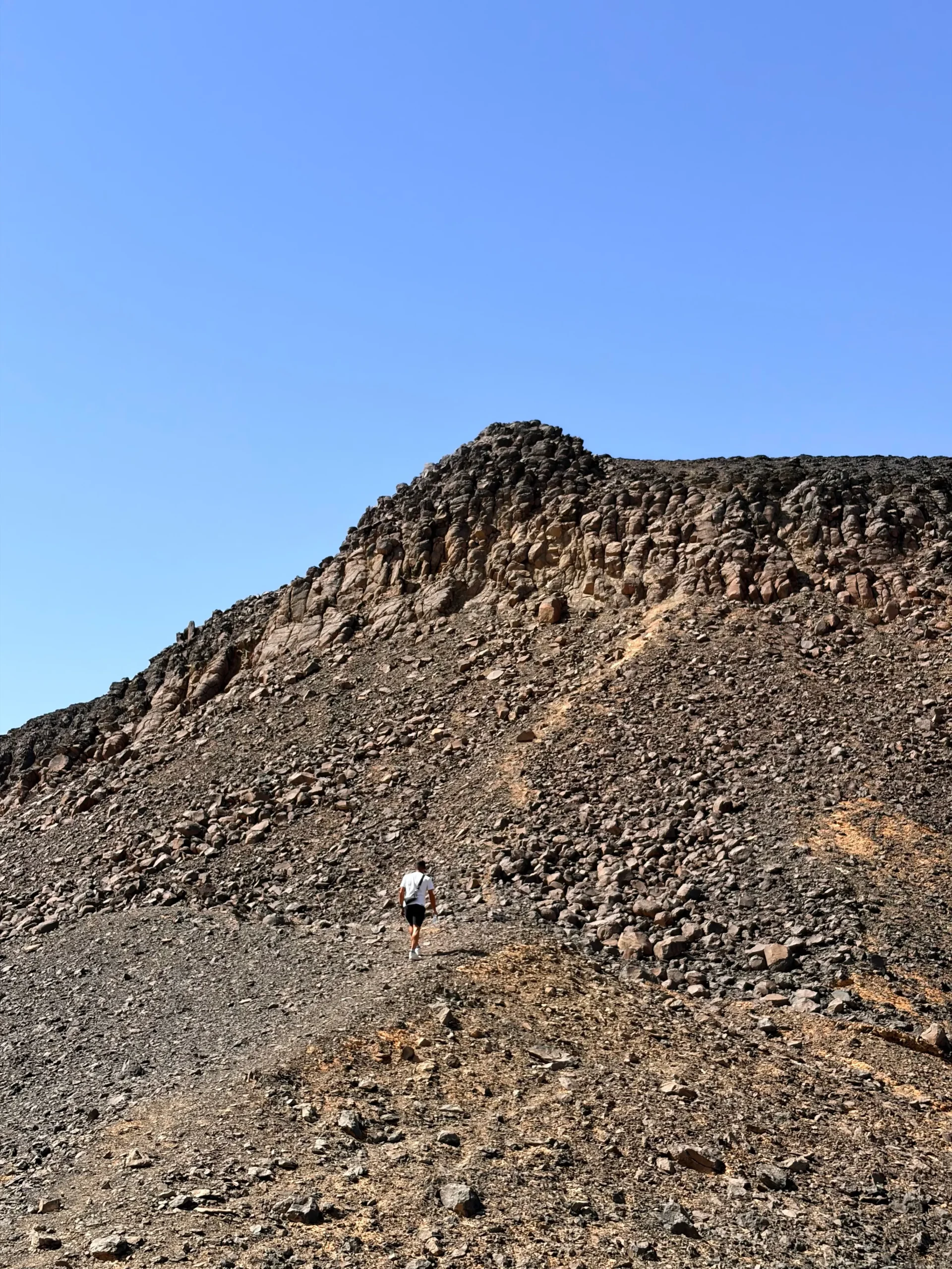Traveler hiking a volcanic hill in the Black Desert near Bahariya Oasis during the 2027 solar eclipse expedition