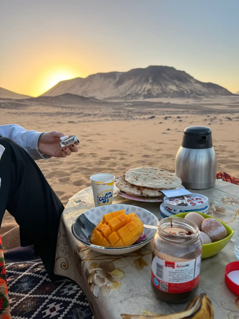 Breakfast with fruit, bread and hot drinks served in front of desert mountains