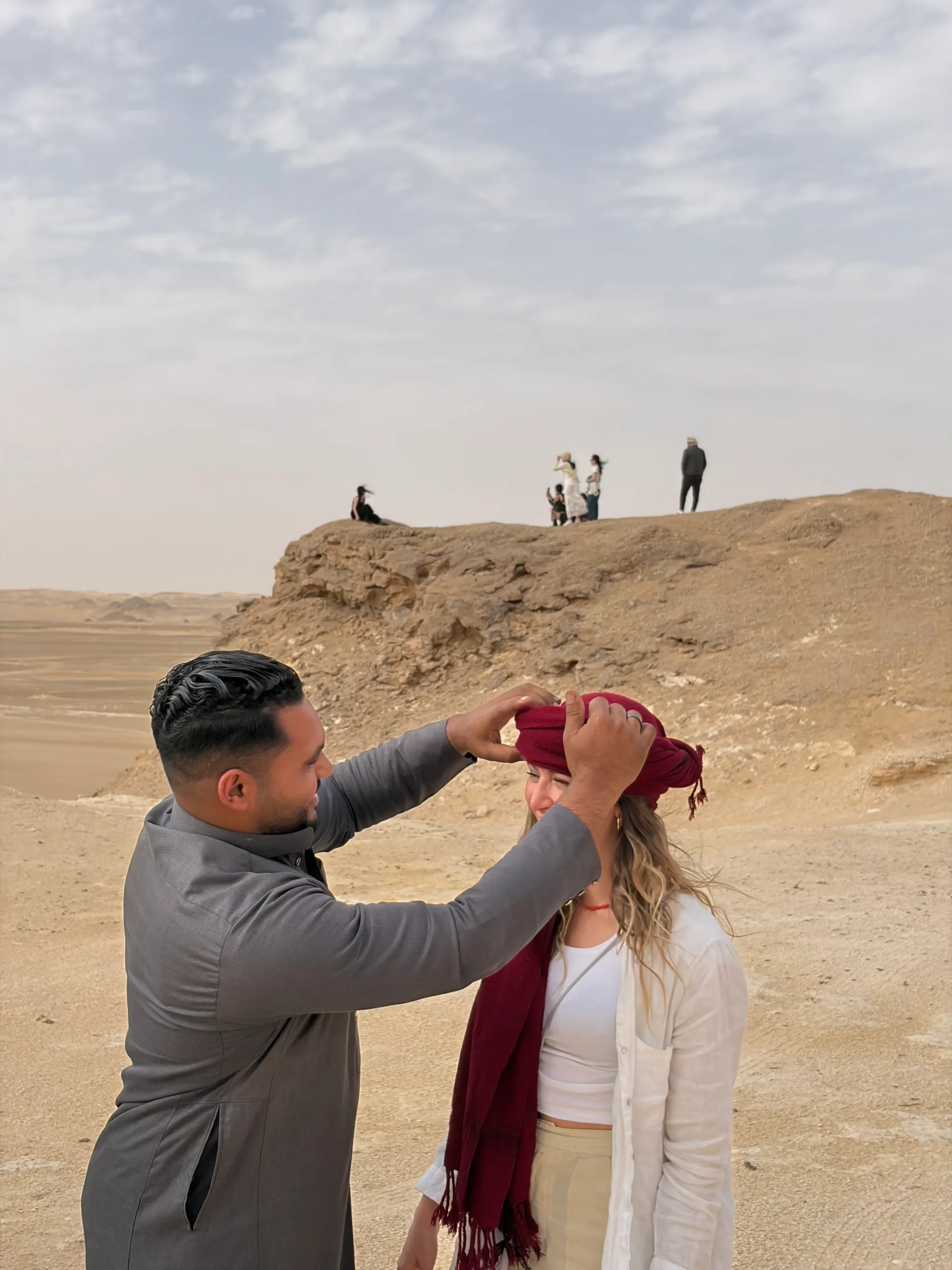 Local Elzaghandi guide helping a traveler adjust a traditional headscarf in Egypt's Western Desert