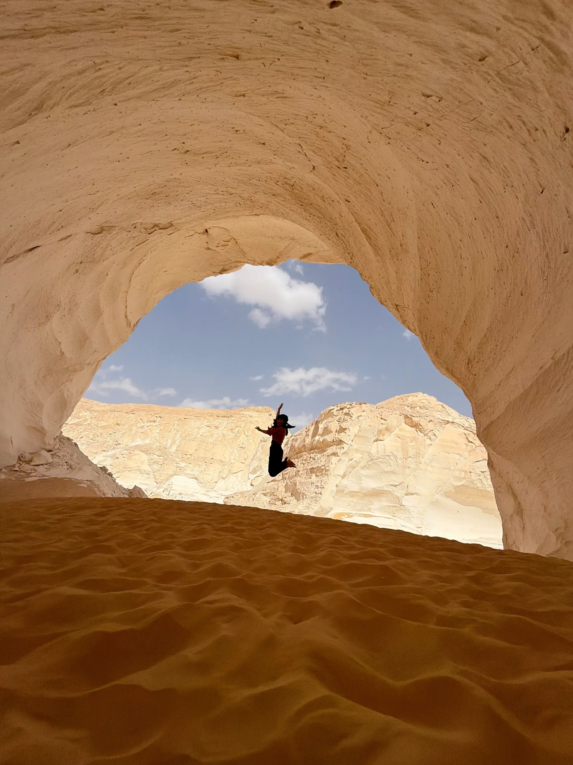 Travelers beneath the Moon Cave limestone arch during a locally guided White Desert expedition